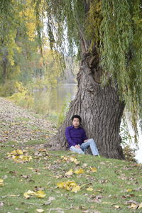 Man sitting by tree on field