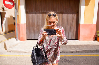 Woman using phone while standing on street