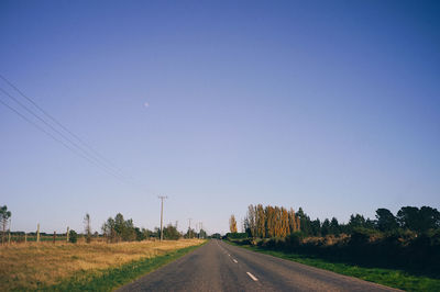 Road amidst field against clear sky