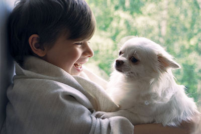 Side view of smiling boy playing with dog