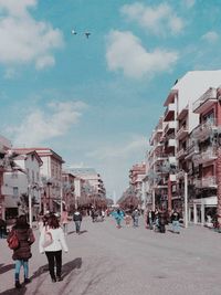 People walking on street in city against sky