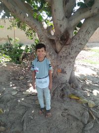 Full length portrait of boy standing by tree