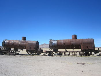 Old ruins on field against clear blue sky