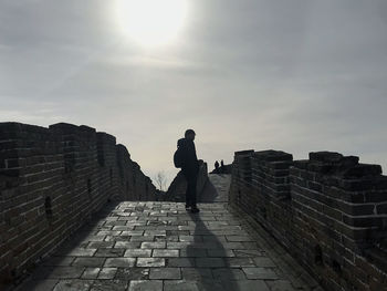 Man standing by wall against sky
