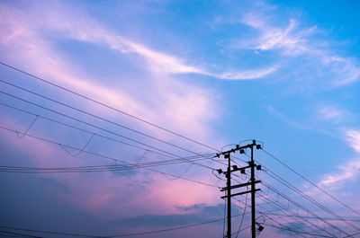 Low angle view of silhouette electricity pylon against sky
