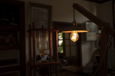 Close-up of illuminated light bulb hanging from ceiling