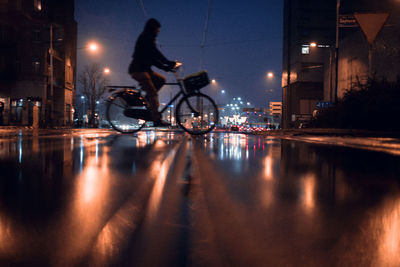 Man riding bicycle on illuminated street at night
