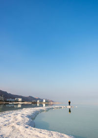 Man on beach against clear sky during winter