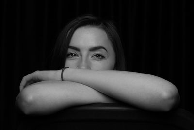 Portrait of young woman sitting on chair in darkroom