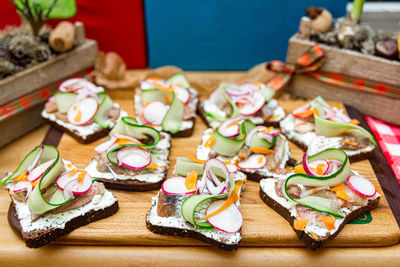 Sandwiches with salted herring, cucumber and radish on a wooden board. many servings.