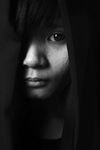 Close-up portrait of young woman against black background