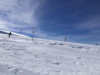 Low angle view of cables over ski slope against blue sky