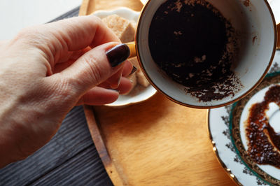 High angle view of hand holding coffee cup on table