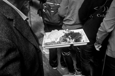 Midsection of man holding food in plate by people