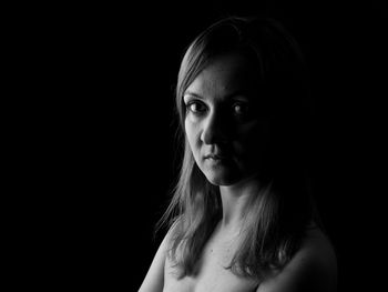 Portrait of young woman against black background