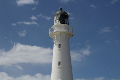 Low angle view of lighthouse by building against sky