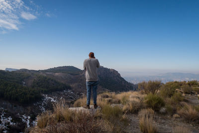 Rear view of man standing on landscape against sky