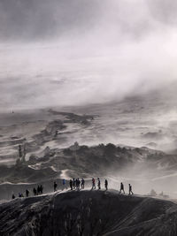 People on mountain against cloudy sky