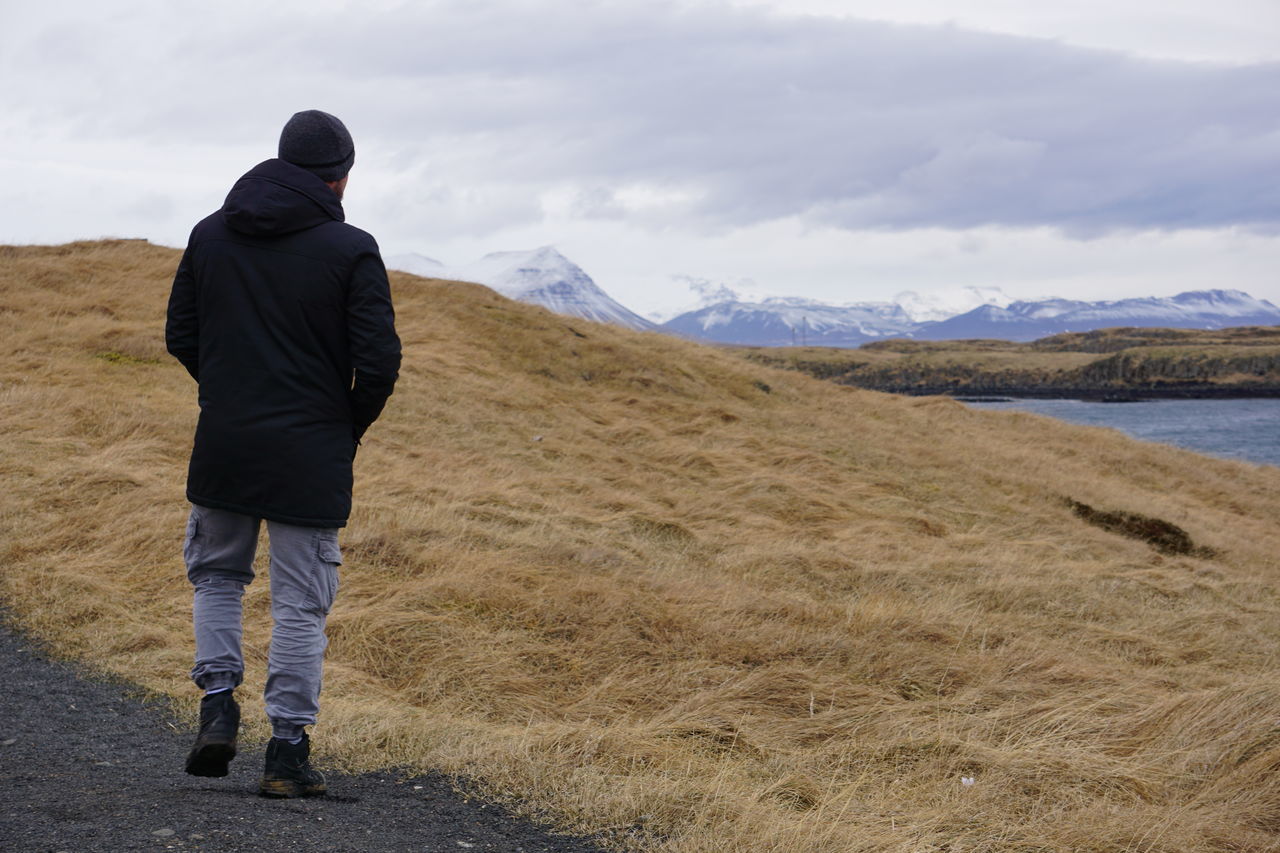 REAR VIEW OF MAN STANDING ON MOUNTAIN