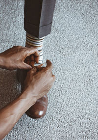Cropped hands of person tying shoelace for man