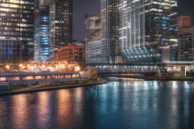 Illuminated buildings by river at night