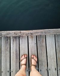 Low section of woman standing on pier over lake