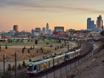 Train in city against sky during sunset