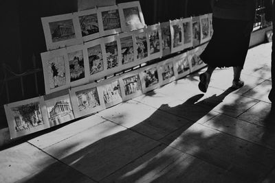 Low section of woman walking by photos displayed for sale