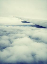Cropped image of airplane wing over clouds