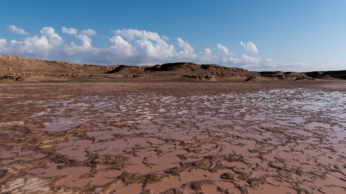 Gathered water in a arid lake in dasht e lut or sahara desert with cloudy sky