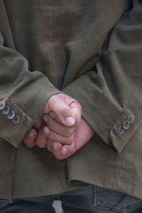 Midsection of man with hands behind back