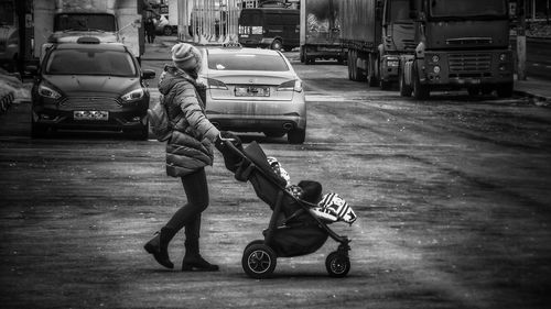 Side view full length of woman pushing baby carriage on road