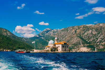 Buildings by sea against blue sky