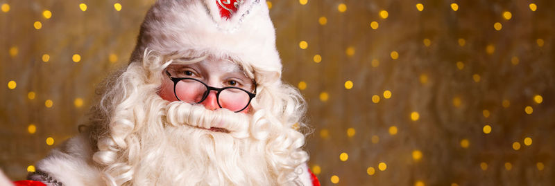 Portrait of santa claus in glasses looking at camera against background