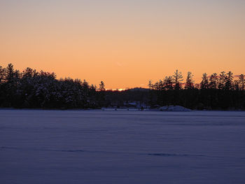 Scenic view of snow covered landscape against sky at sunset