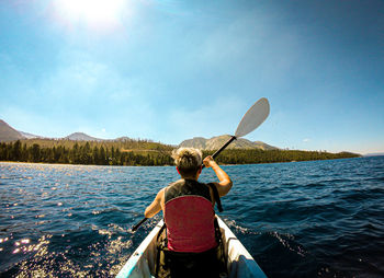 Rear view of woman on boat in sea against sky