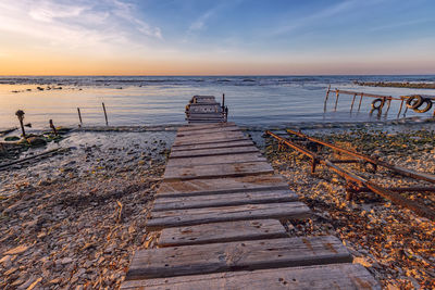 Wooden posts on beach against sky during sunset