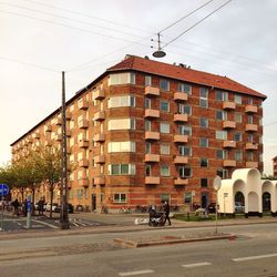 Road by buildings in city against sky