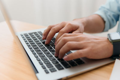 Cropped hands using laptop on table