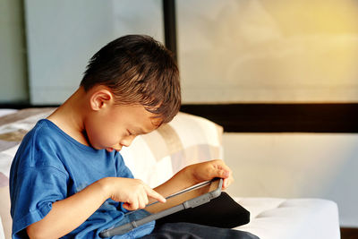 Side view of boy using digital tablet at home