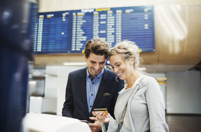 Happy business people looking at credit card in airport