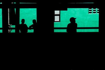Silhouette people against green wall