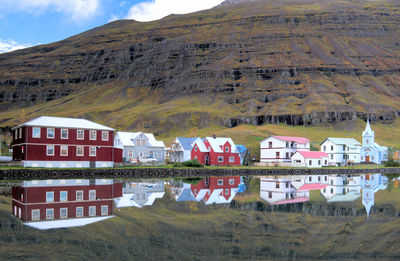 Houses and mountain reflecting on calm lake