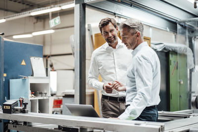 Male engineers discussing over laptop in factory