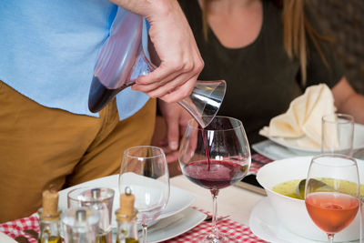 Midsection of man pouring wine in glass