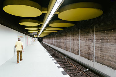Rear view of man standing on railroad station platform