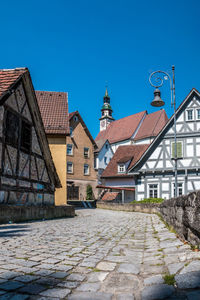 Street amidst buildings against clear blue sky