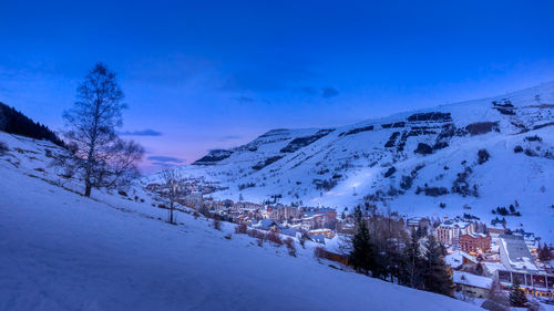 Snow covered houses by buildings against sky