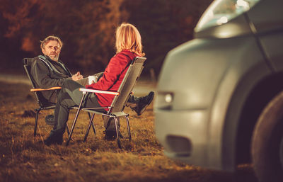 Couple sitting on chair outdoors