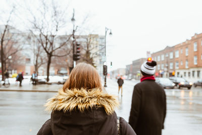 Rear view of people on street in city during winter